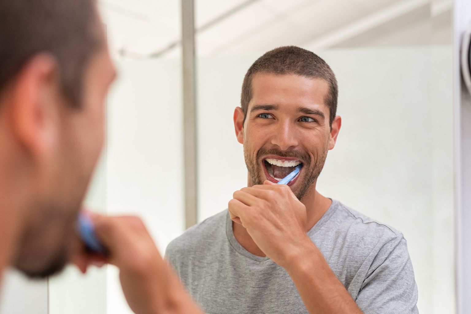 Lachender Mann der sich seine Zähne putzt